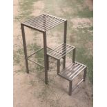 A silver coloured metal stool with steps