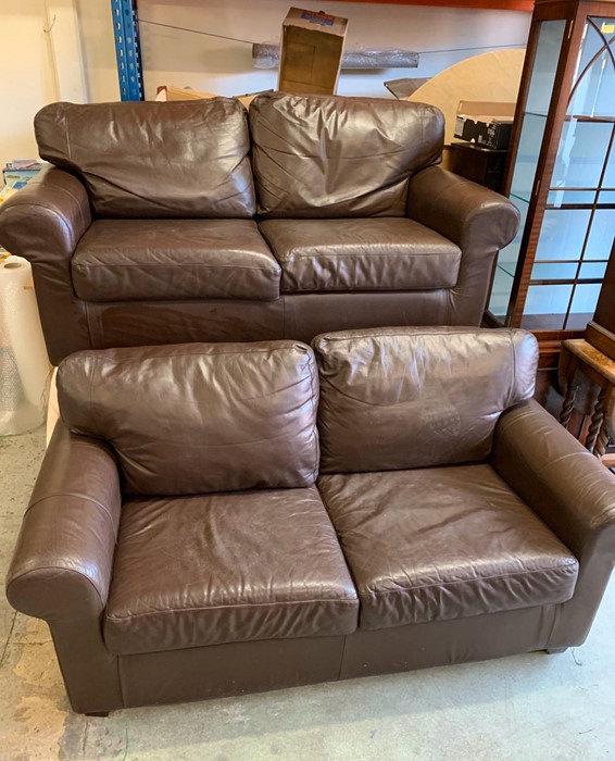 A pair of brown leather two seater sofas
