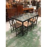 A metal dining table with lower grid shelf and glass top with six matching dining chairs with rushed