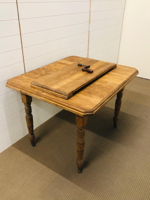 Solid pine kitchen table with insert and original winder, on turned legs with brass castors - Image 2 of 2