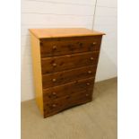 A tall pine chest of drawers with five