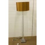 A contemporary floor standing lamp with a crystal effect glass stand and chrome base