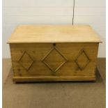 A large pine blanket box decorated with a raised diamond trim to front and sides and cast iron