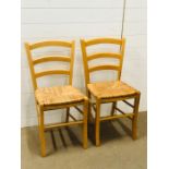 A pair of black ladder back kitchen chairs with rush seats