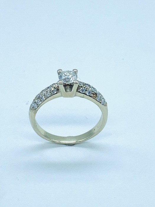 A modern solitaire diamond ring with diamond shoulders in 18 ct white gold setting. Central