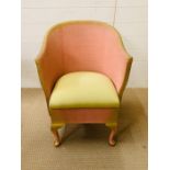 A Lloyd loom chair with pink and green seat pad