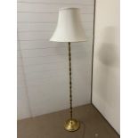 A floor standing brass lamp with white shade