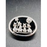 A Silver and Onyx Brooch depicting four cats singing.
