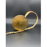 A Vintage Brass Tennis court measuring tape with the measurements and layout engraved on one side.