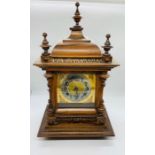 A carved wooden mantel clock with brass base