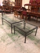 A large metal rectangular coffee table with lower grid shelf and glass top with matching square side