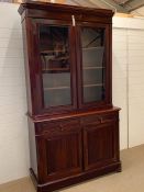 A mahogany bookcase with two glazed doors enclosing adjustable shelves, the base with a square edged