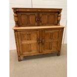 A light oak sideboard with cupboard top and bottom and turned decorative pillars to side. (H124cm