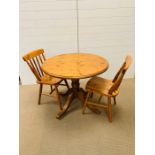 A Ducal pine round dining table with two chairs