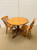 A Ducal pine round dining table with two chairs