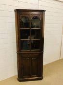 A tall oak corner cupboard with an upper glazed door (locked)