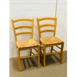 A pair of ladder back kitchen chairs with rush seats