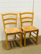 A pair of ladder back kitchen chairs with rush seats