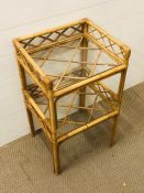 A bamboo/cane small floor standing unit with two glass shelves