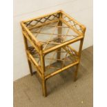 A bamboo/cane small floor standing unit with two glass shelves