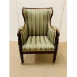 A mahogany framed wing armchair with reeded arms on brass castors (H100cm)