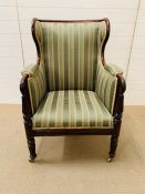 A mahogany framed wing armchair with reeded arms on brass castors (H100cm)