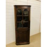 A tall oak corner cupboard with an upper glazed door (locked)