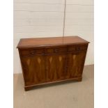A Yew wood sideboard with three panelled doors to front and drawers above H90cm x D 46cm x L115cm