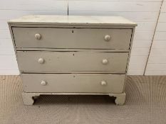 A painted three drawer chest of drawers with bun handles (H94cm W105cm D55cm)