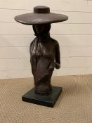 A metal sculpture of a women wearing a large brimmed hat