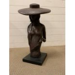 A metal sculpture of a women wearing a large brimmed hat