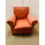 An upholstered club armchair, raised on bun feet and castors (H82cm W98cm D94cm)
