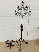 A large wrought iron floor standing candelabra and a table top candelabra