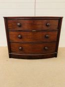 A bow fronted chest of drawers, flanked by reeded columns with bun handles (H80cm W98cm D54cm)