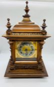 A carved wooden mantel clock with brass base