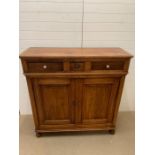 A mahogany side cupboard on bun feet with three drawers to top (H140cm W136cm D50cm)