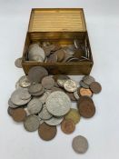 A small metal tin contains a variety of coins, various countries, denominations etc