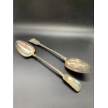 A pair of large white metal serving spoons