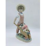 A Lladro figure of a boy pushing a wheelbarrow of flowers