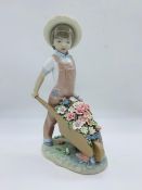 A Lladro figure of a boy pushing a wheelbarrow of flowers