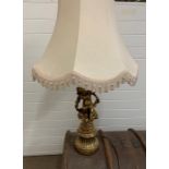 A table lamp with a cream shade of a gilt figure of a girl sat on a leaf