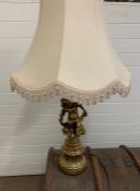 A table lamp with a cream shade of a gilt figure of a girl sat on a leaf