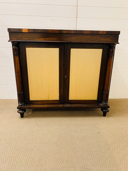 A Rosewood Chiffonier with a pair of doors to front with silk panels, flanked by turned columns