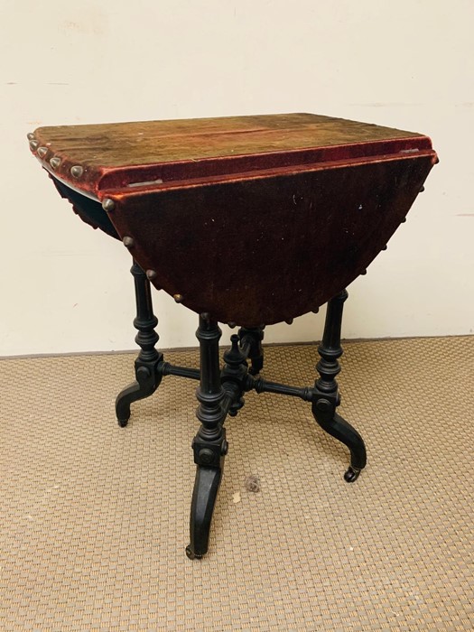 Velvet and studded drop sided occasional table on ebonized legs and castors