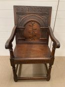 A Wainscot chair oak panel open arm chair with scrolled arms, plank seat raised on turned legs.