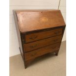 A mahogany bureau, the slant front with inlaid shell pattern opens to an arrangement of drawers