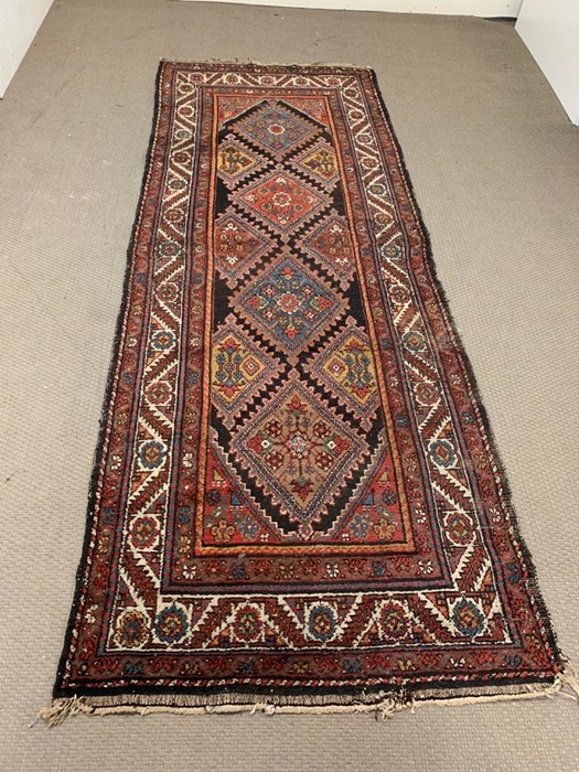 A red, orange and blue coloured runner with a diamond pattern to center (296cm x 110cm)