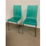 A pair of aqua acrylic dining chairs on metal frame of mid century design