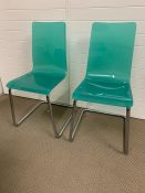 A pair of aqua acrylic dining chairs on metal frame of mid century design