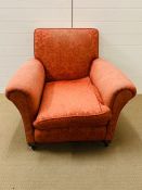 An upholstered club armchair, raised on bun feet and castors (H82cm W98cm D94cm)